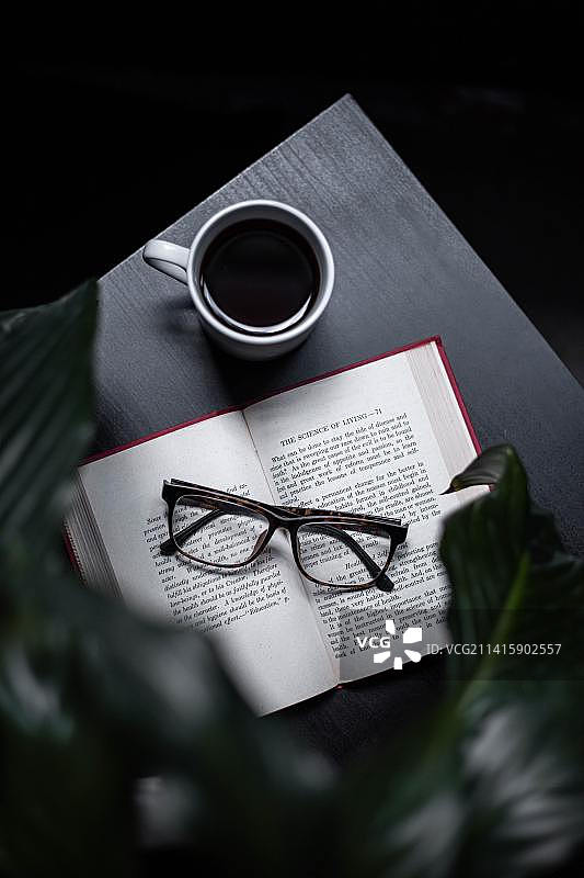 高角度视角的眼镜与书和咖啡杯在桌子上，印度尼西亚图片素材