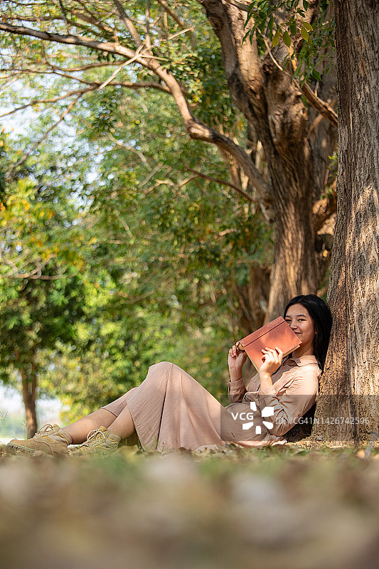 一个女人坐在一棵大树下看书图片素材