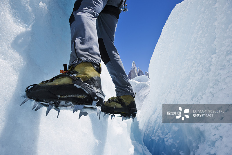 一個人的腳掛在冰凍的山坡上圖片素材