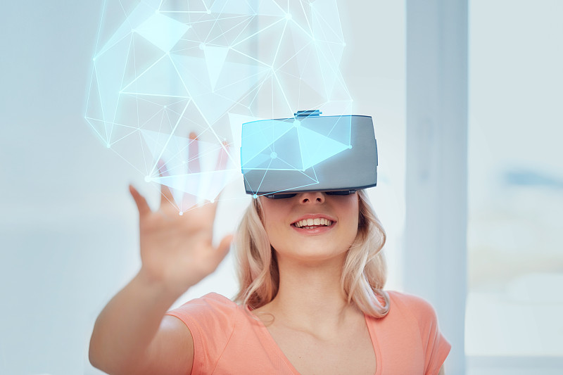 技術，增強現實，網絡空間和人的概念-快樂的年輕女子戴著耳機或3d眼鏡在家里玩游戲看虛擬投影的低多邊形形狀圖片素材