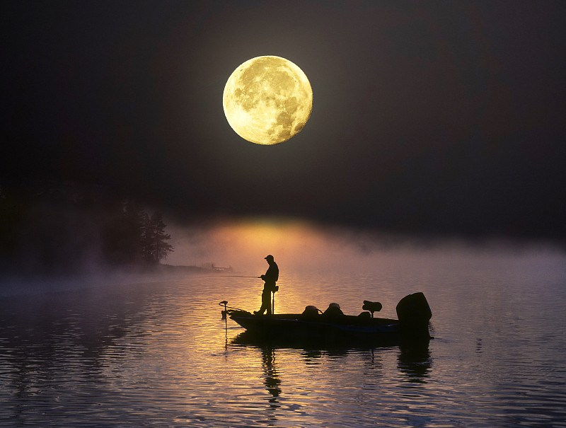 滿月下，一人在漁船上圖片素材