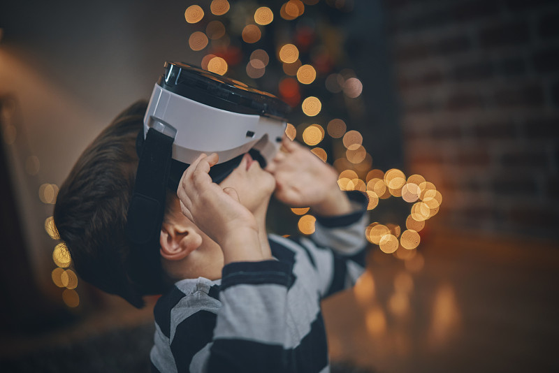 在舒適的圣誕氛圍中，孩子們在客廳玩VR眼鏡圖片素材