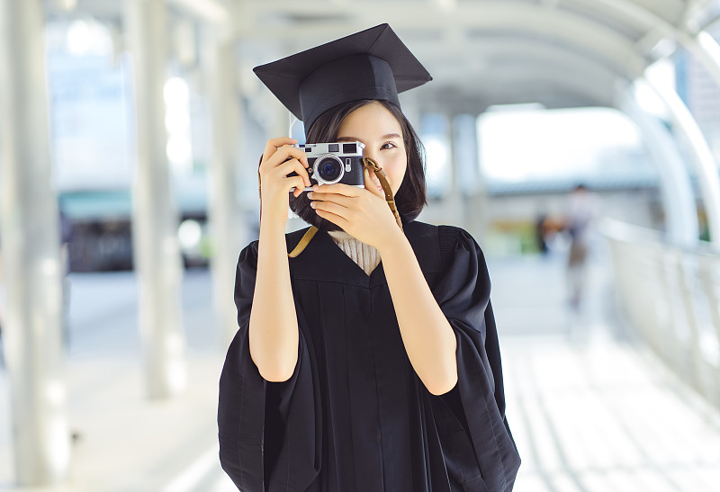 穿著畢業禮服在城市拍照的女人的肖像圖片素材