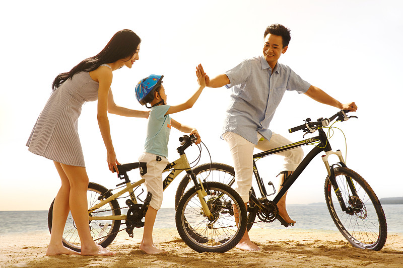 一家三口在沙灘上騎自行車圖片素材