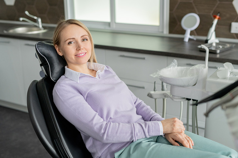 年輕貌美的當代牙科女病人坐在診所微笑圖片下載