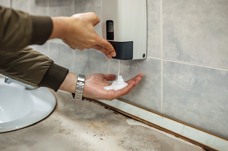 戴口罩的男子在公共廁所洗手圖片素材