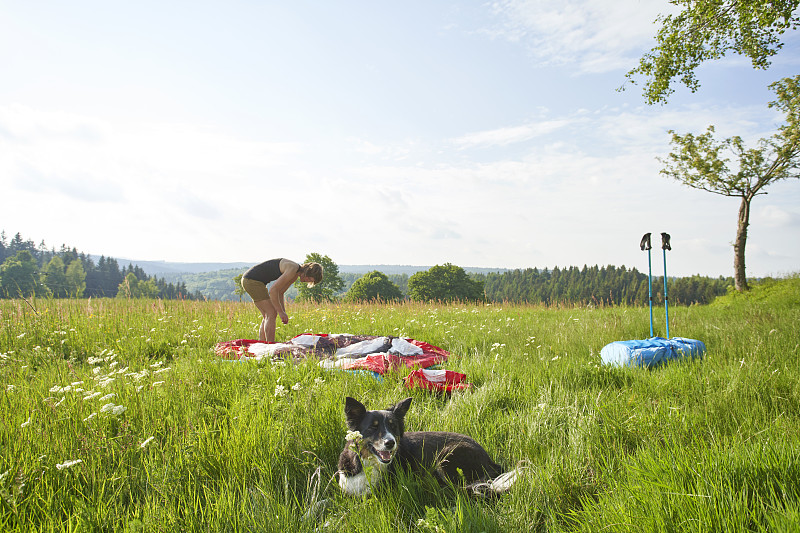在陽光明媚的日子里，孤獨的女性在茂盛的草地上搭帳篷攝影圖片