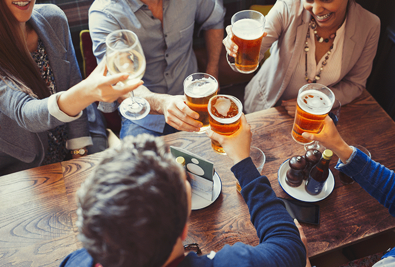 俯瞰朋友们在酒吧的餐桌上庆祝，举杯互敬啤酒图片素材