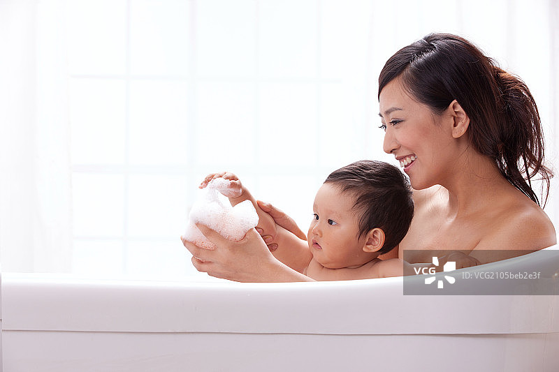 母亲和婴儿坐在浴缸中洗澡图片素材
