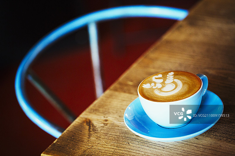专业咖啡店。一个蓝色的瓷杯碟，上面有起泡的咖啡。图片素材