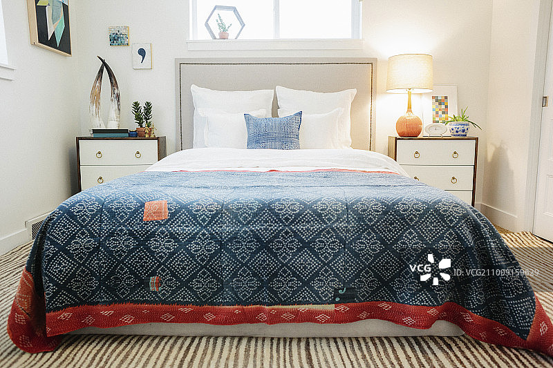 一间公寓的卧室，里面有一张双人床和一个复古的仿古图案的拼花床罩。图片素材