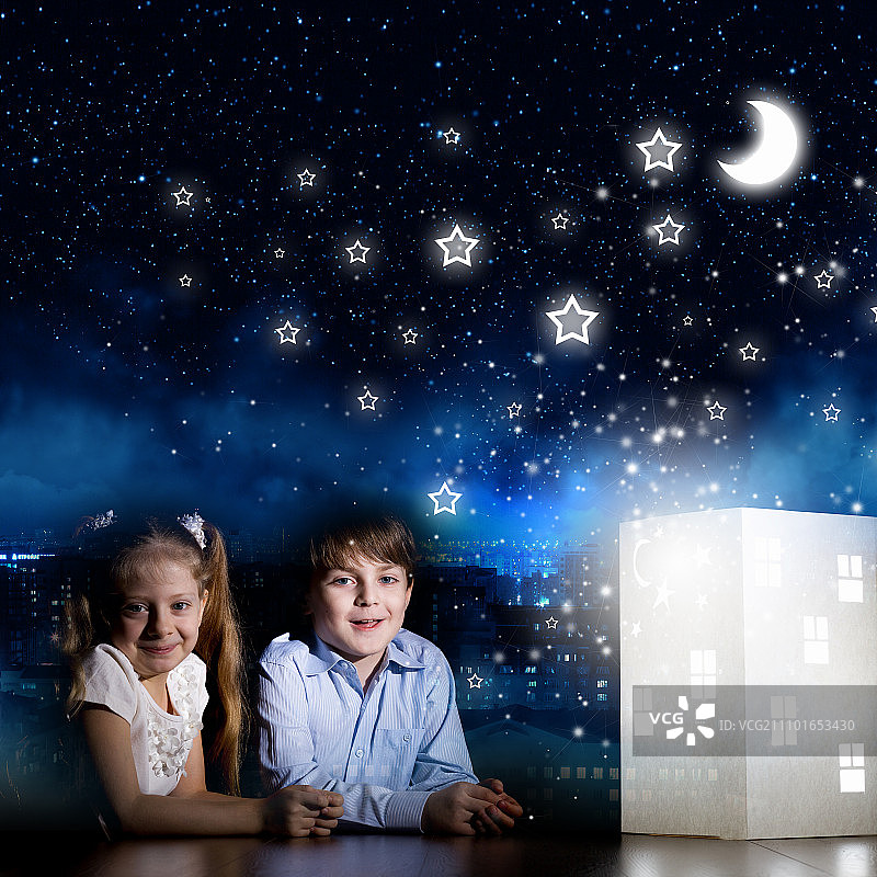 晚上做梦。可爱的小男孩和小女孩在看房子模型图片素材