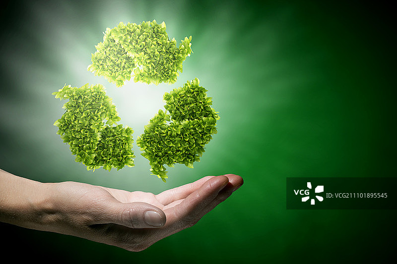 回收的概念。手握绿色回收标志的特写图片素材