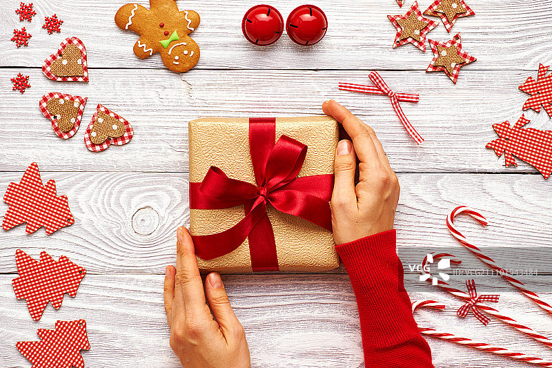 女性的手在圣诞礼物和自制的姜饼饼干与手工装饰在木制的背景图片素材