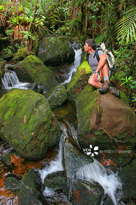 委内瑞拉特普伊罗赖马山的森林里，一名男子在岩石上休息图片素材