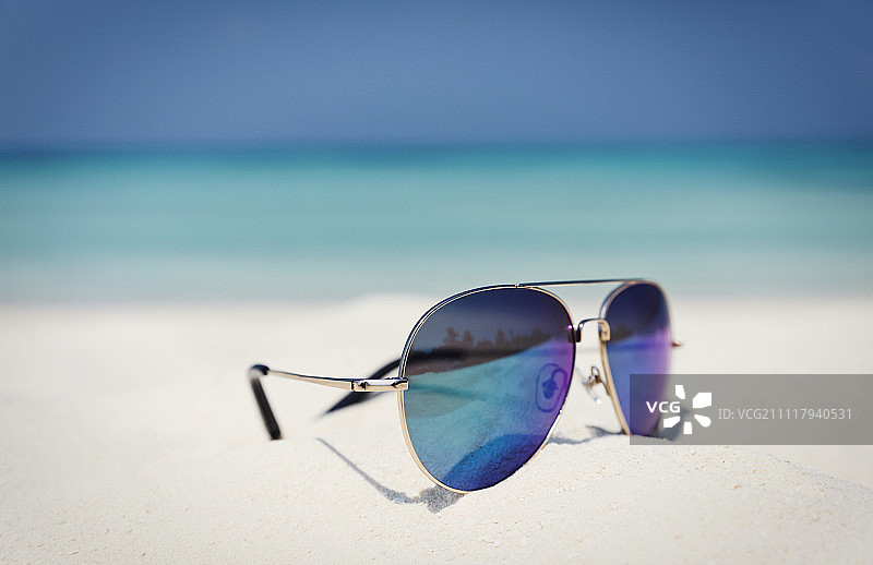 近距离飞行太阳镜在阳光明媚的热带海滩上的沙子图片素材