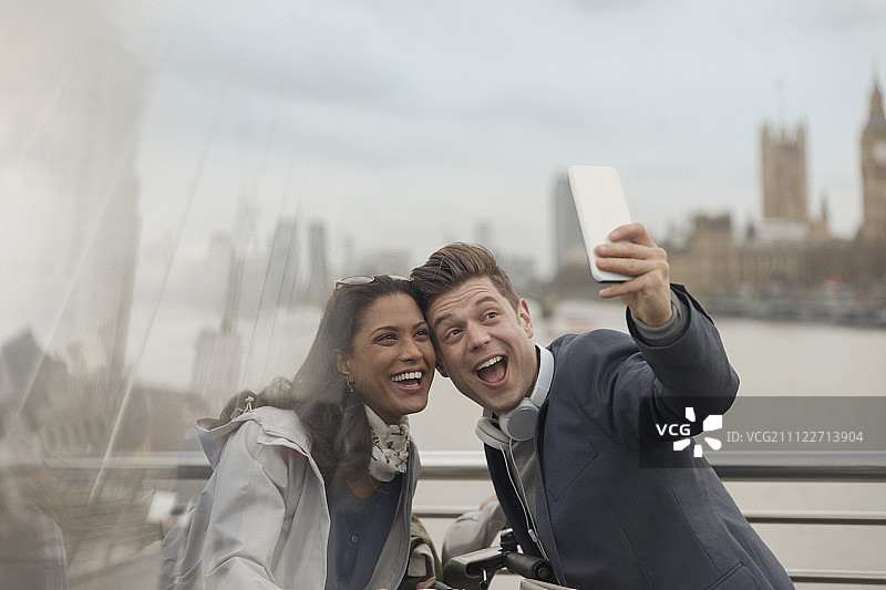 好玩的游客夫妇在英国伦敦的一座桥上用手机自拍图片素材