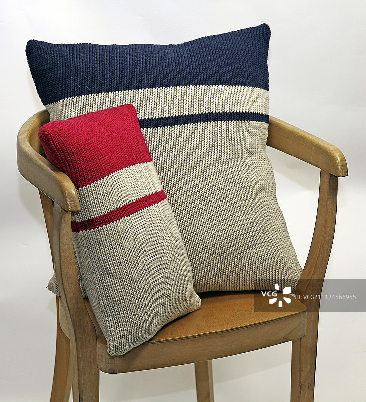 木椅上有两个编织的蓝红相间的靠枕图片素材