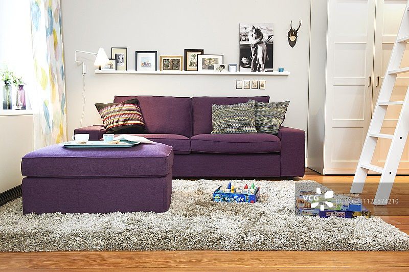 紫色的沙发，蒲团，梯子和墙上的相框图片素材