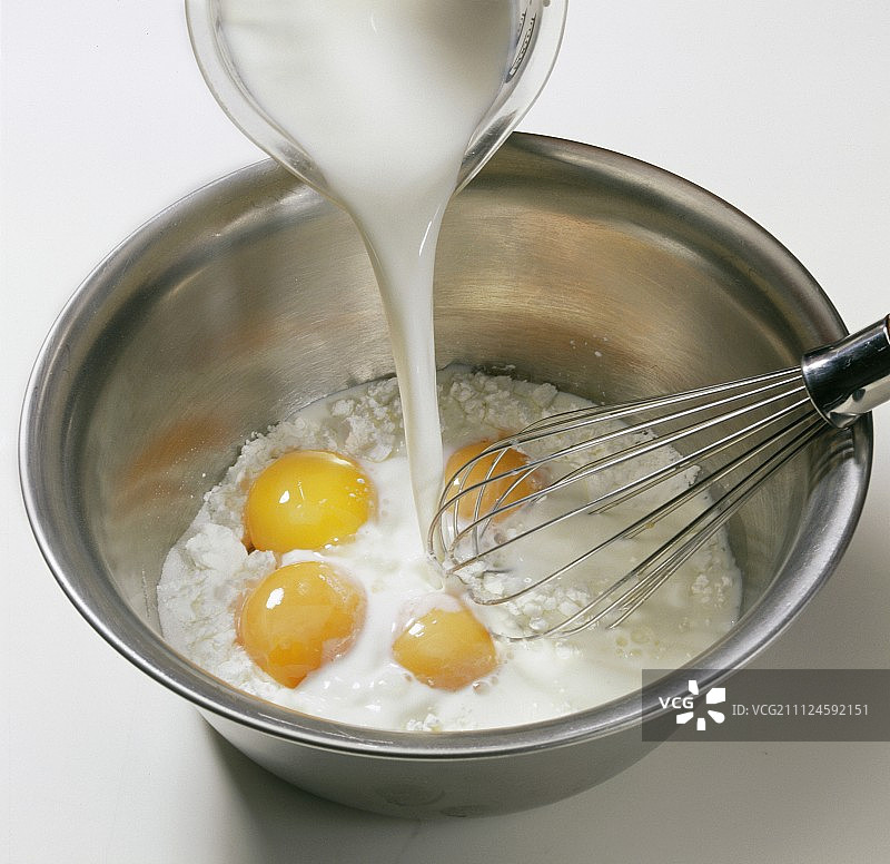 将牛奶倒入面粉、蛋黄和糖的混合物中图片素材