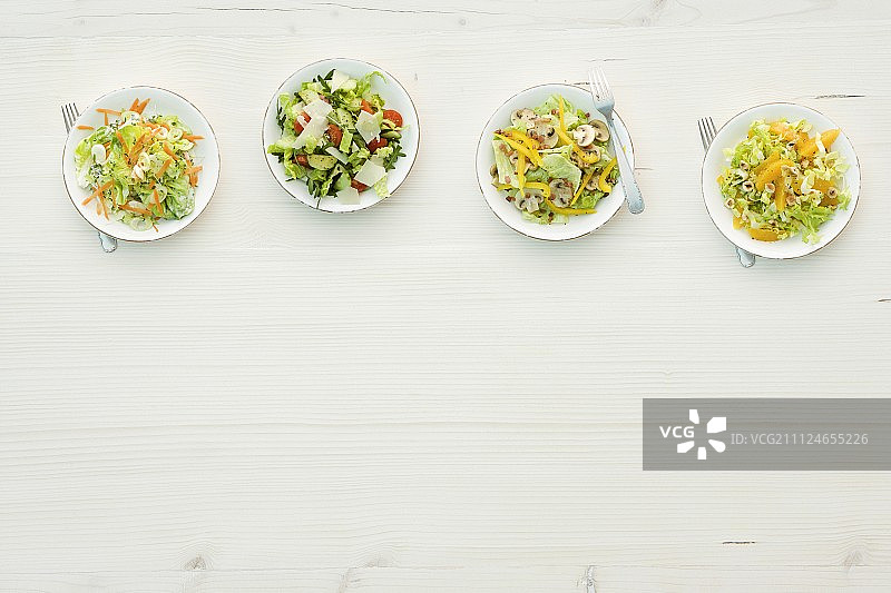 四种不同的沙拉在盘子里，俯视图片素材