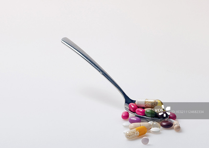 勺子与药片，药丸，胶囊和糖衣在白色的背景图片素材
