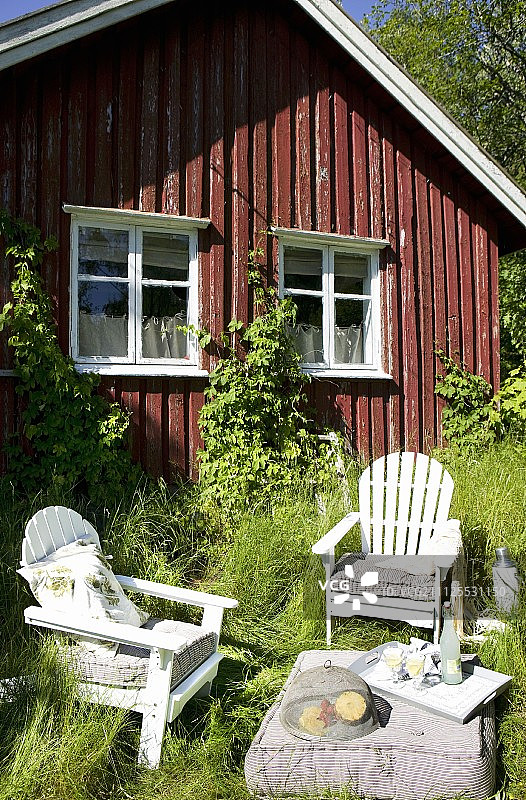 田园诗般的，亲密的座位区在高草前的斯堪的纳维亚小屋图片素材