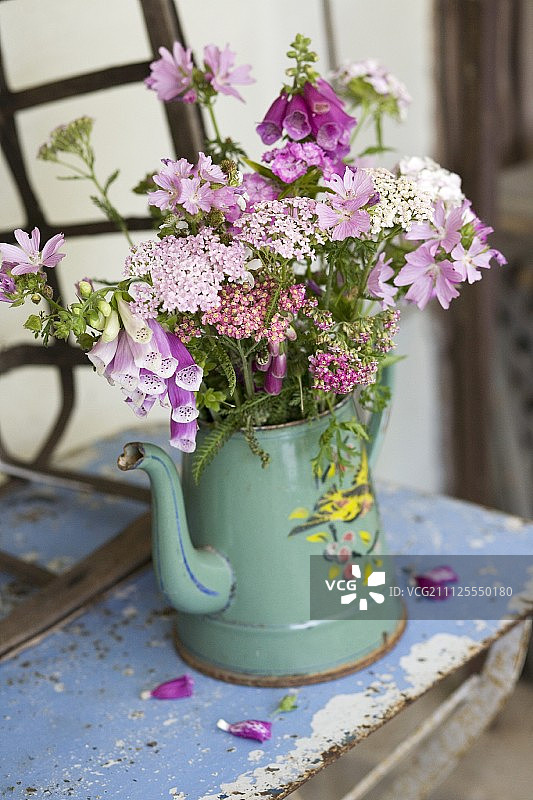 古色古香的金属桌子上的珐琅咖啡壶里的一束花园花图片素材
