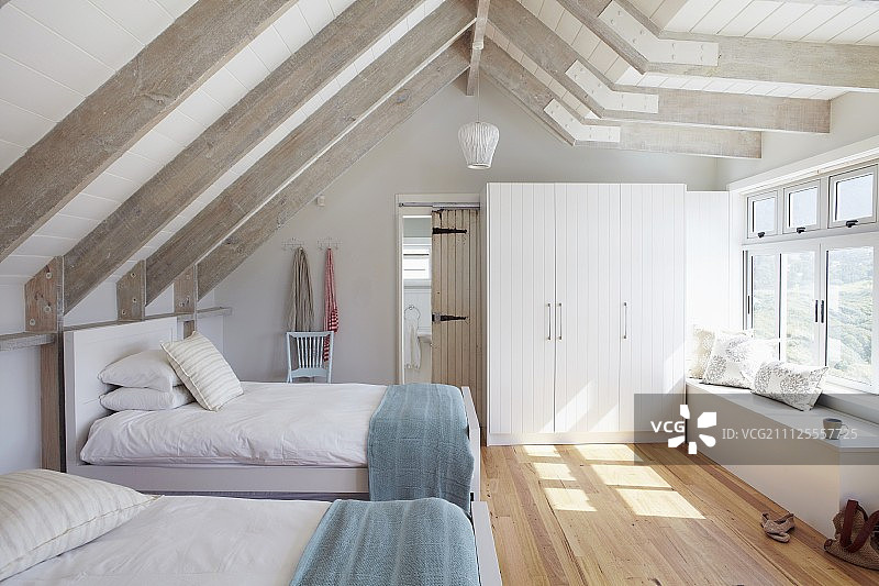 客房有两张床，在明亮的阁楼房间，白色的木梁和拼花地板图片素材