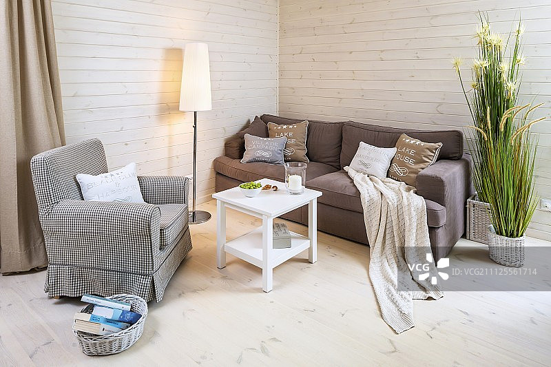 标准灯与苍白的灯罩在舒适的休息区沙发和扶手椅之间，靠浅色漆木镶板图片素材