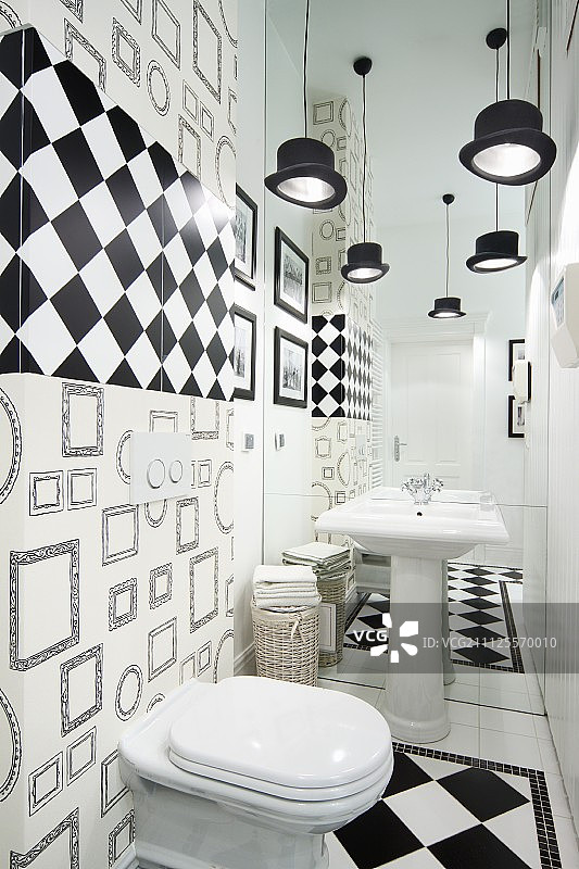 卫生间以黑白两色装饰，配有大礼帽吊灯和底座水槽后的镜面墙产生的空间错觉图片素材