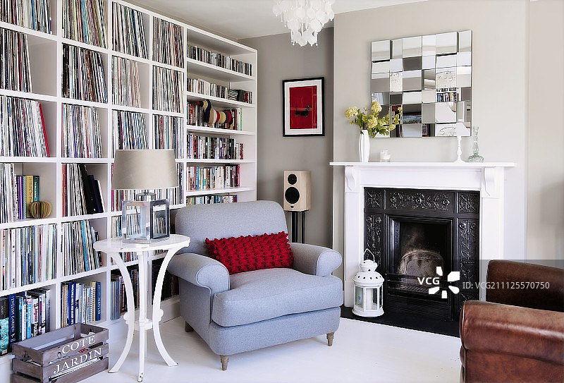 淡蓝色扶手椅和圆边桌，紧挨着开放式壁炉和白色书柜靠墙而立图片素材