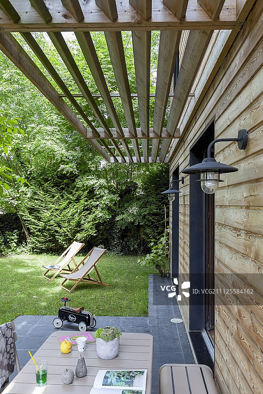 从阳台上的桌子到花园外的躺椅和木制的板条遮阳伞图片素材