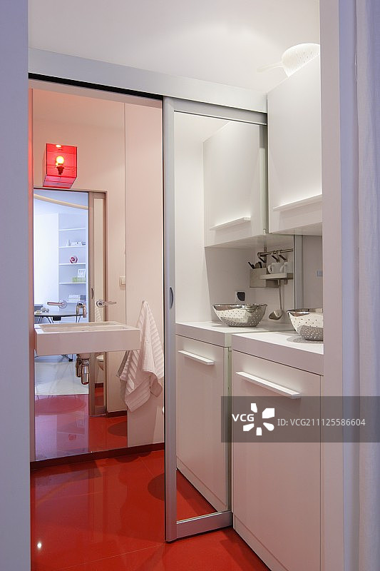 小厨房与打开镜面滑动门通向浴室与连续的橙色地板图片素材