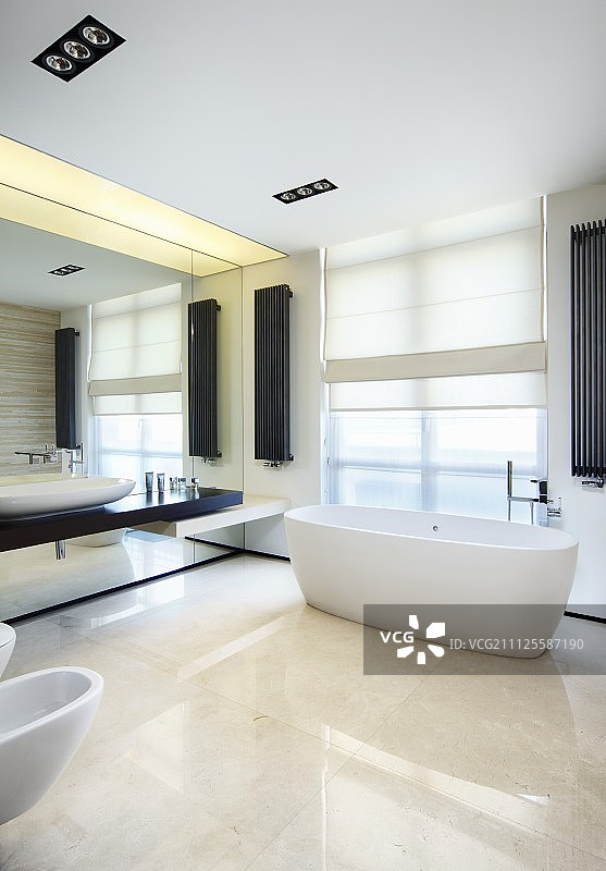 酷，白色设计师浴室与黑暗的口音形成壁挂式散热器和盥洗台安装在连续镜面墙上图片素材