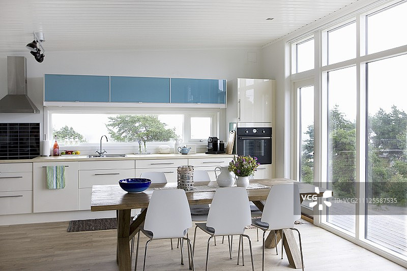 浅色的厨房柜台和用餐区，在开放式厨房的木桌周围有白色椅子图片素材