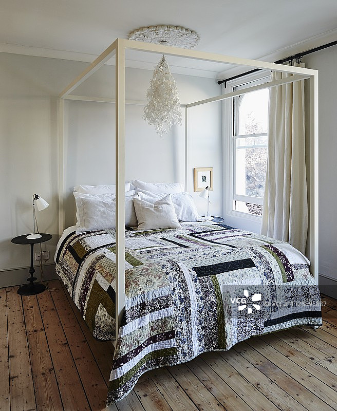 在简单的卧室里，双人床和白色的顶棚框架上的拼接罩和木地板图片素材
