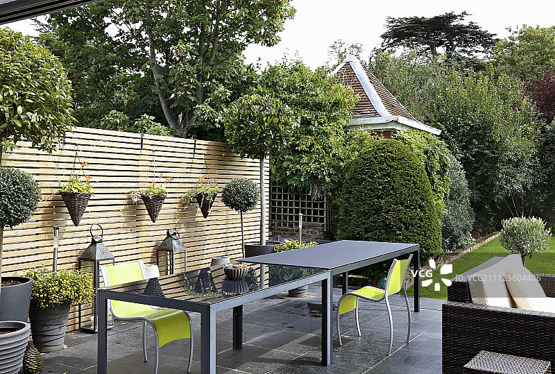 优雅的灰色户外桌子和霓虹灯绿色椅子在板条木屏风前的露台上图片素材