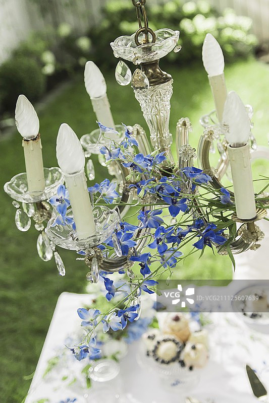 用飞燕草装饰的水晶吊灯悬挂在花园的咖啡桌上图片素材