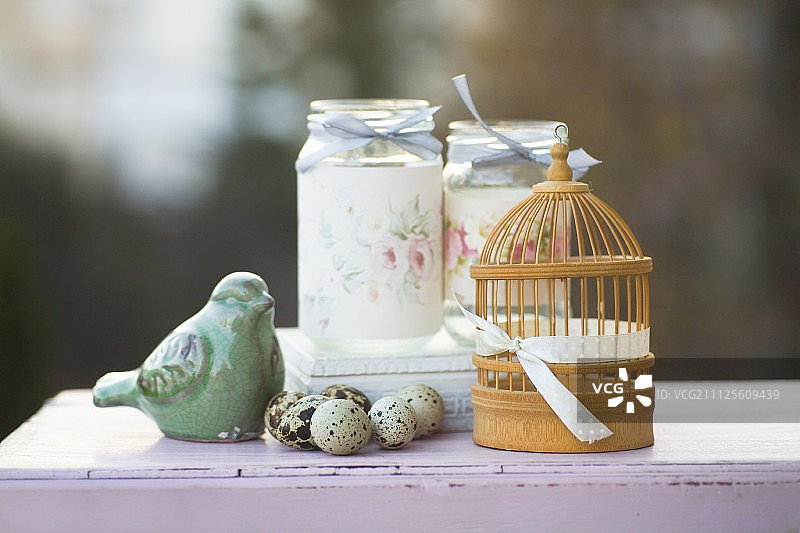 鹌鹑蛋，鸟饰品，迷你鸟笼和装饰螺旋罐的浪漫安排图片素材