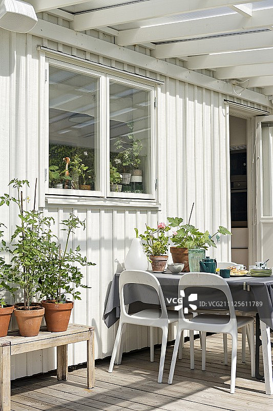 白色的塑料椅子围绕着白色的木制房子外面的露台上的桌子图片素材