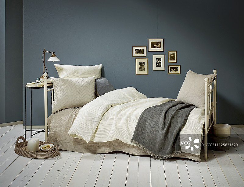 复古风格的金属床，枕头和毯子在自然色调的蓝灰色墙壁图片素材