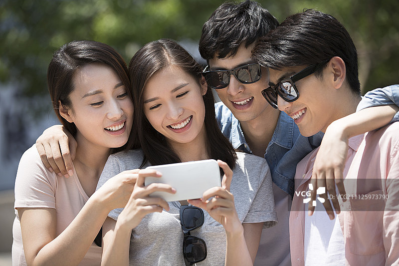 四个年轻人户外玩手机图片素材