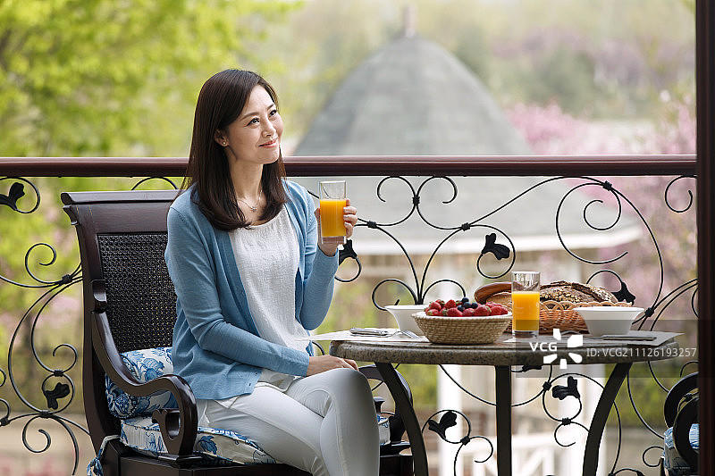 中年女人在阳台上吃早餐图片素材