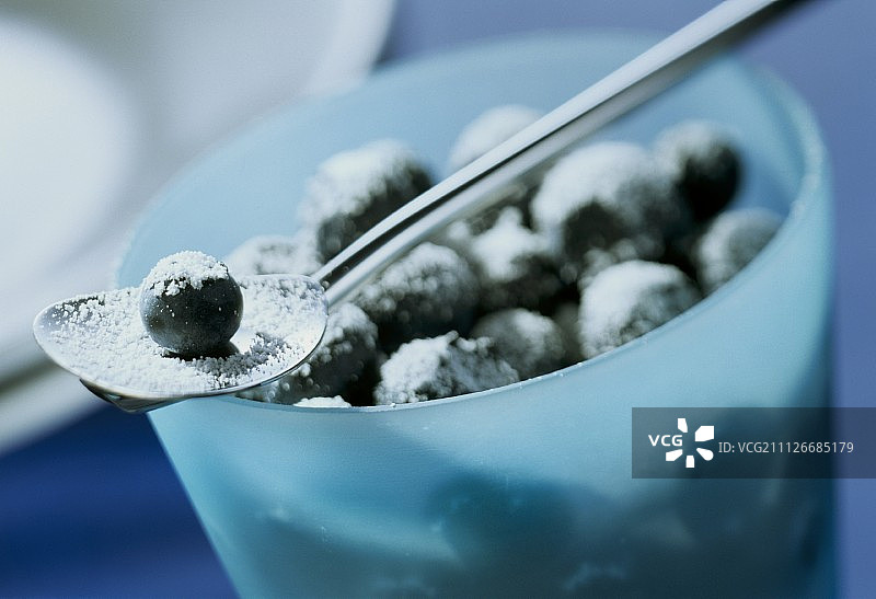 加糖的蓝莓放在蓝色的碗里和勺子里图片素材