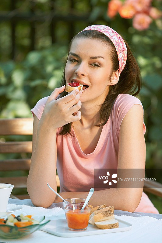 一个女人正在花园里吃早饭图片素材