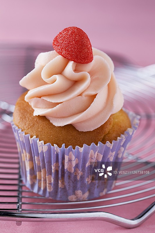 一个用草莓奶油和草莓夹心糖装饰的纸杯蛋糕图片素材