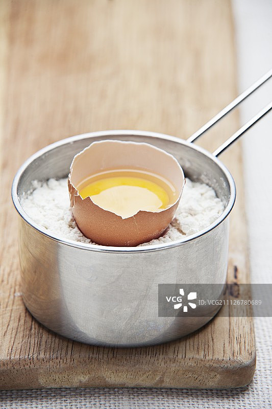 面粉炖锅里的一个有裂缝的鸡蛋图片素材