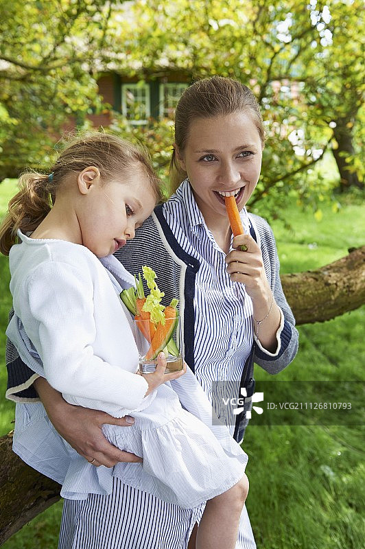 一个女人和一个小女孩在花园里吃蔬菜沙拉图片素材