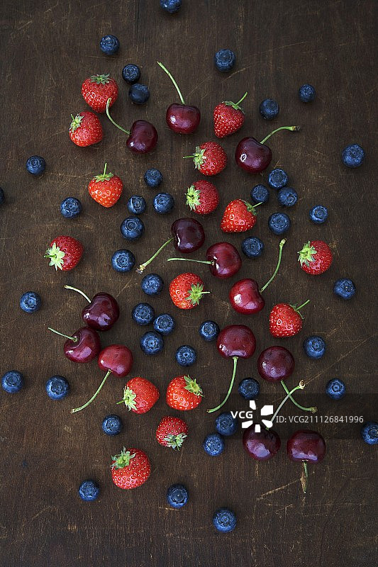 夏天的水果放在木板上(草莓、蓝莓和樱桃)图片素材